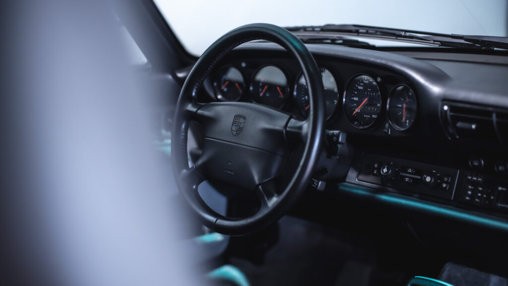 interor shot of driver seat steering wheel in focus and dashboard porsche 993 c2 grey